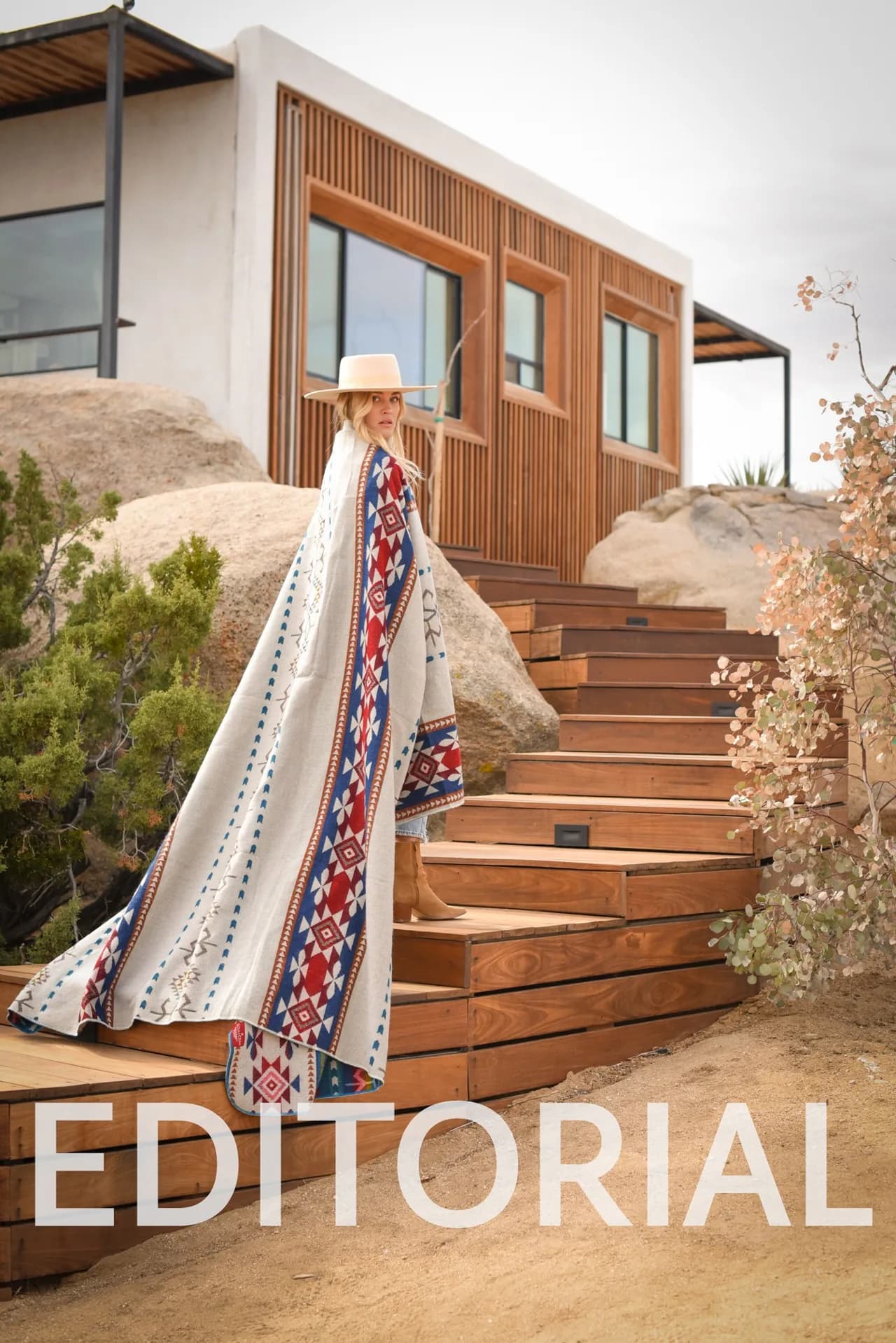 Fashion editorial, model in a patterned cape on cedar stairs